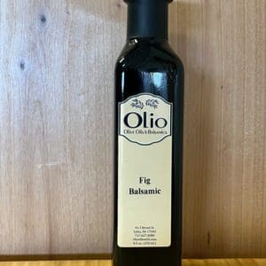 A bottle of Fig Balsamic vinegar on a wooden surface.