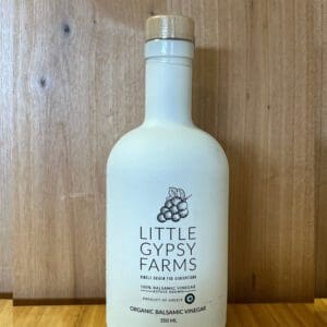A white bottle of Little Gypsy Farms lotion on a wooden surface.