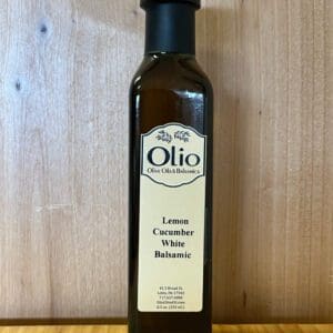 A bottle of lemon cucumber white balsamic vinegar on a wooden surface.