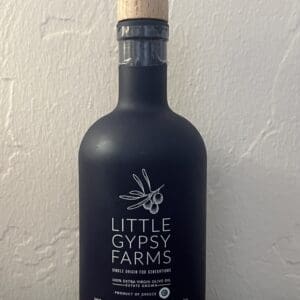 A black bottle of Little Gypsy Farms olive oil with a wooden cap.