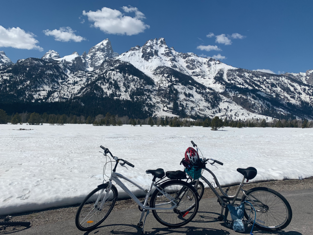 Two bikes parked near a snowy mountain under a blue sky.