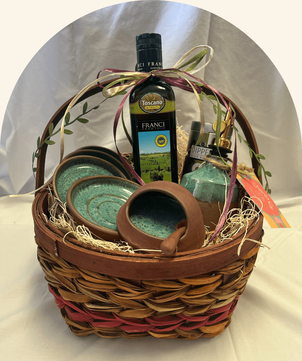 A gift basket with olive oil and ceramic pottery items.