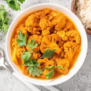Bowl of spicy cauliflower curry garnished with fresh cilantro.