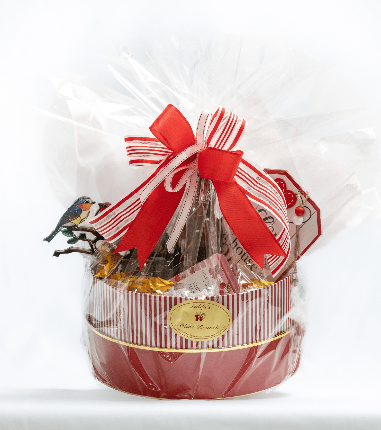 Festive gift basket wrapped with clear plastic and a red bow.