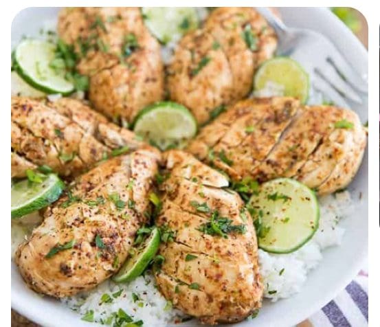 Grilled chicken drumsticks garnished with lime slices on a bed of rice.