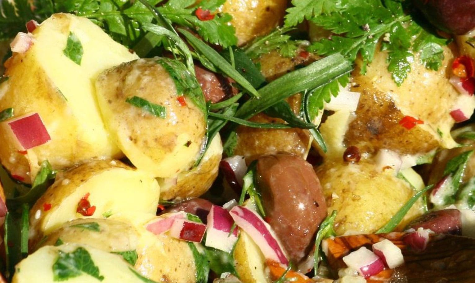 Close-up of a fresh potato salad with herbs and radishes.