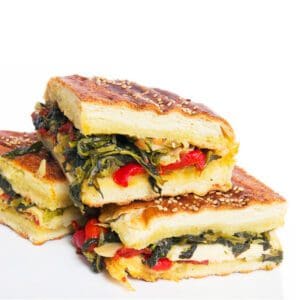 Stack of grilled vegetable sandwiches with melted cheese.