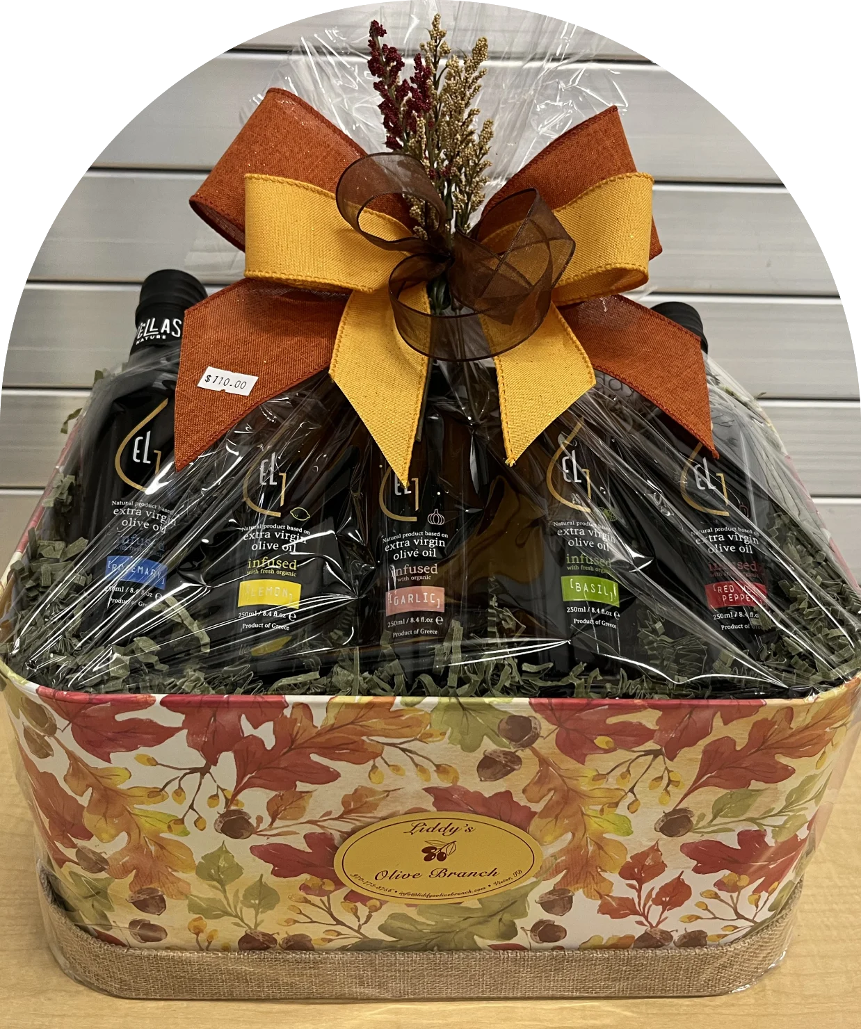 Gift basket with assorted items wrapped in cellophane and topped with a large brown and yellow bow.